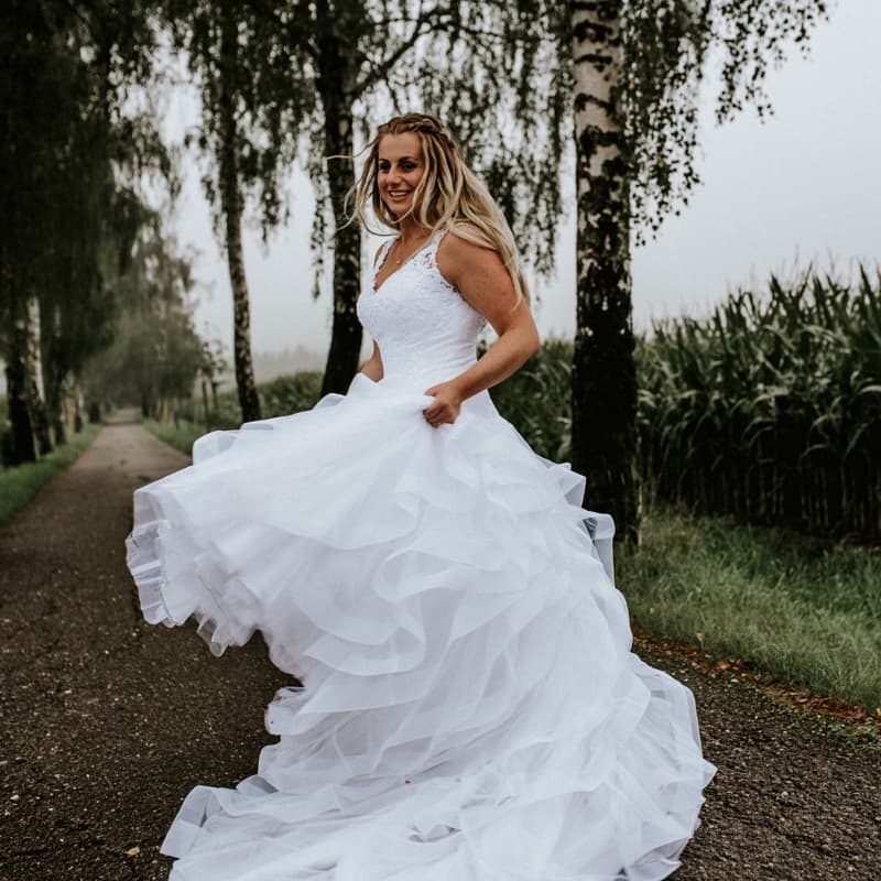 Katka in a wedding dress on a birch-lined road